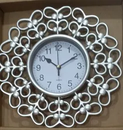 Silver plastic decorative wall clock with a flower design frame.