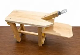 Traditional manual coconut scraper with a serrated metal blade attached to a wooden bench